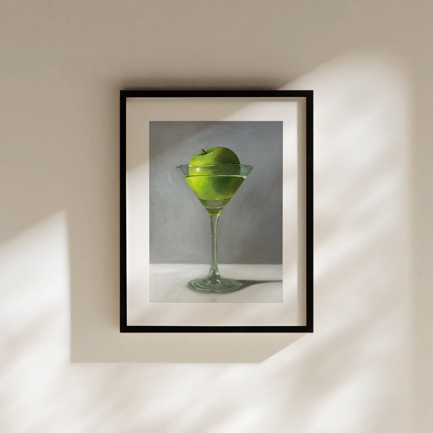 This artwork features a whimsical take on the traditional Apple Martini cocktail. A single granny smith apple rests inside a martini glass on a light, reflective surface with dramatic light and shadows.