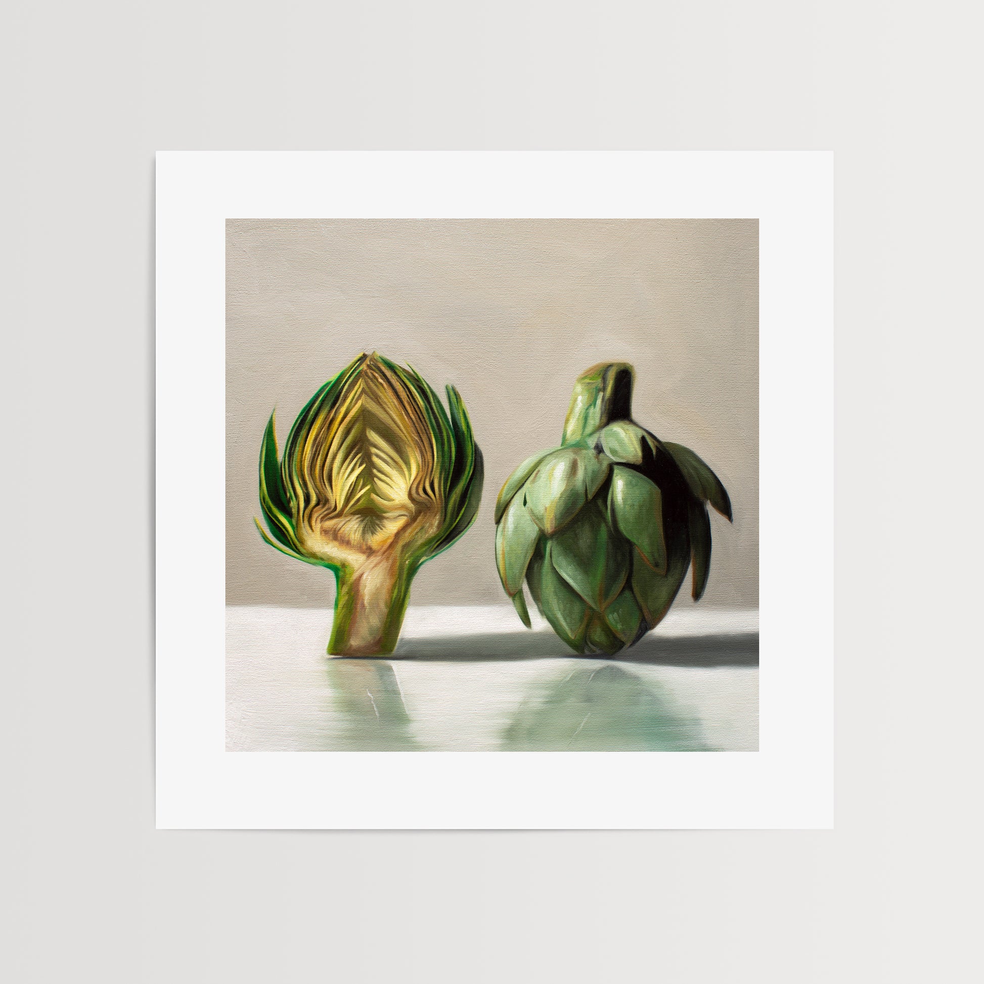 This artwork features an artichoke sliced in half an strategically placed on a light reflective surface.