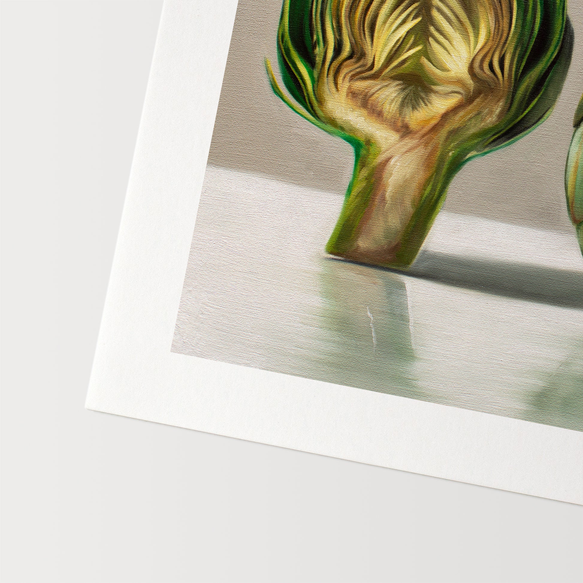 This artwork features an artichoke sliced in half an strategically placed on a light reflective surface.