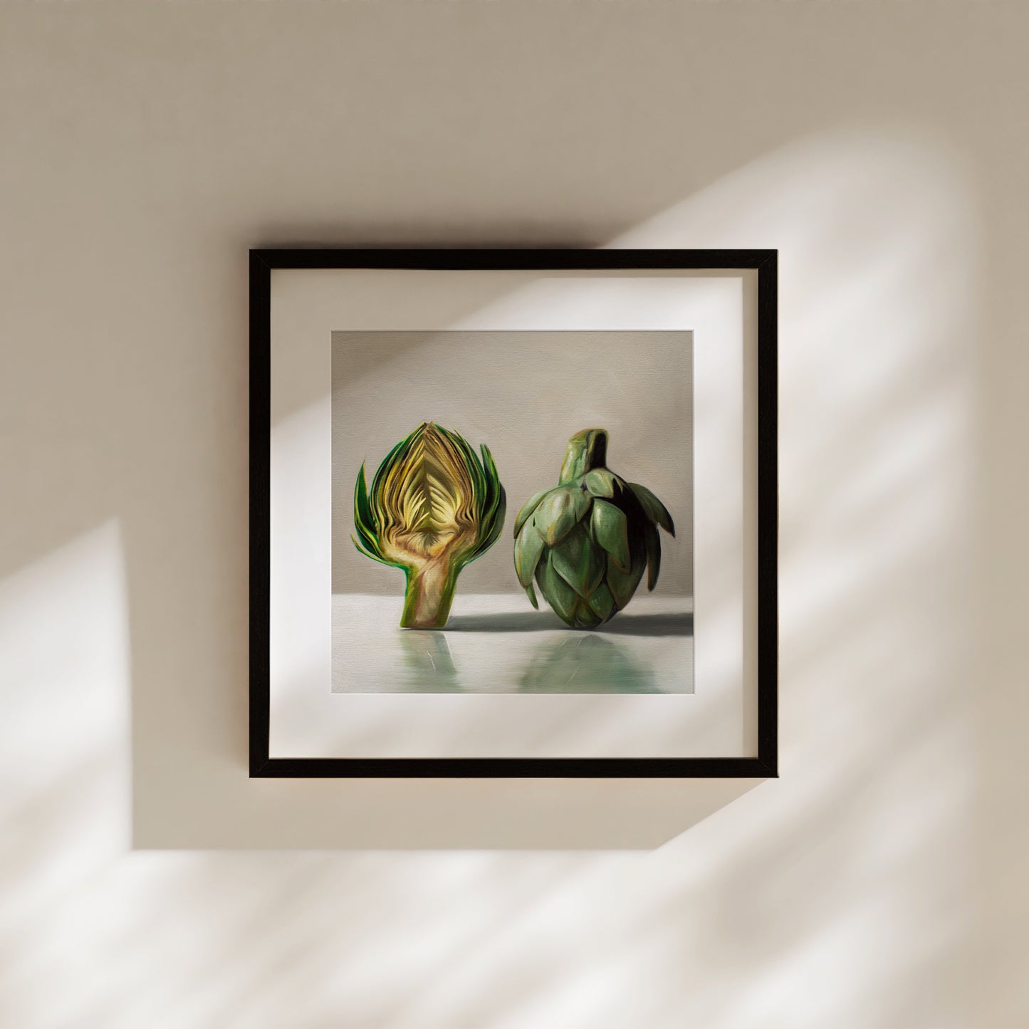 This artwork features an artichoke sliced in half an strategically placed on a light reflective surface.