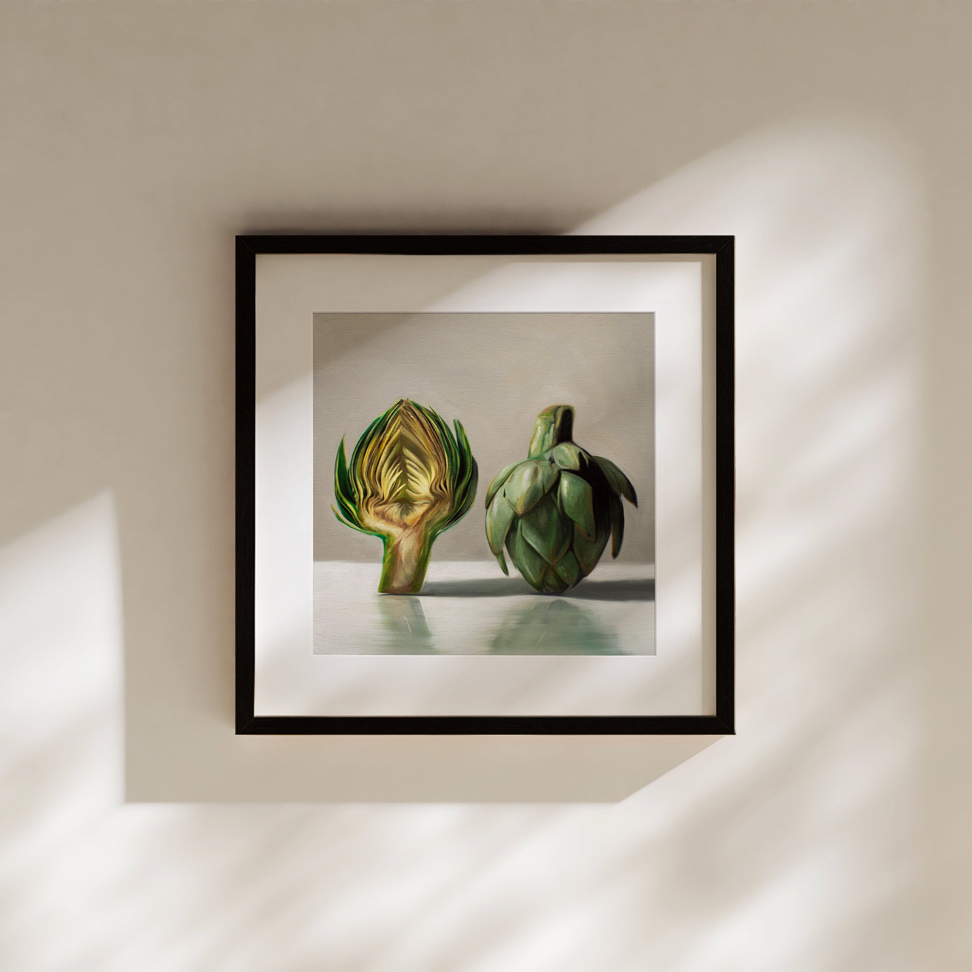 This artwork features an artichoke sliced in half an strategically placed on a light reflective surface.