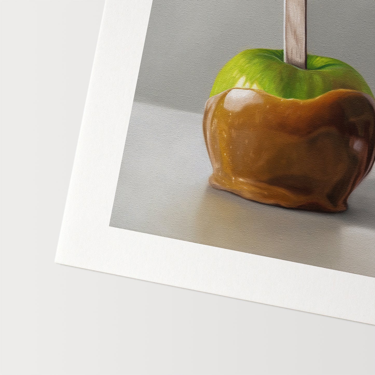 This artwork features a freshly dipped caramel apple resting on a light, reflective surface.