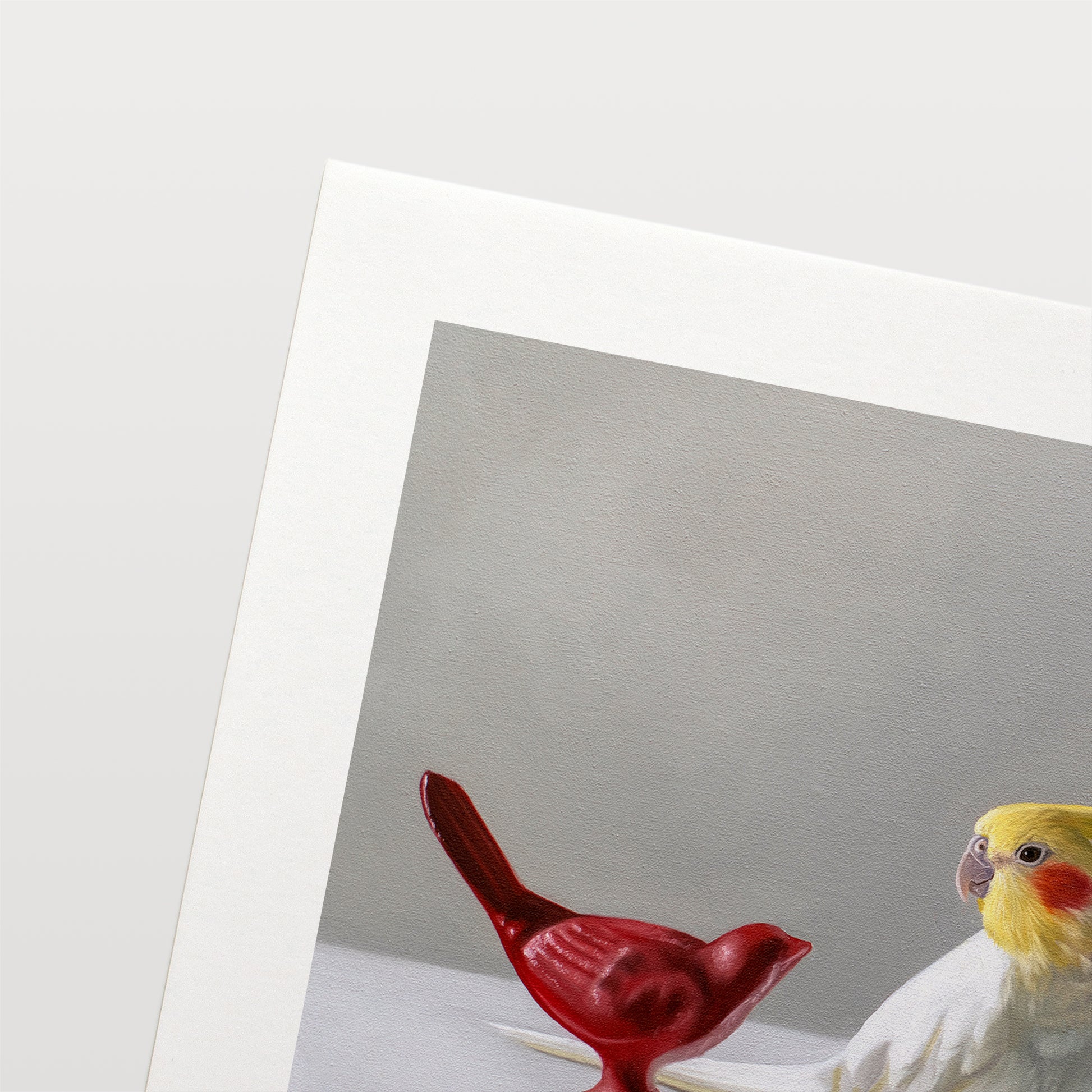 This artwork features a white cockatiel standing in between a red and blue bird figurine on a light, reflective surface with dramatic lighting.