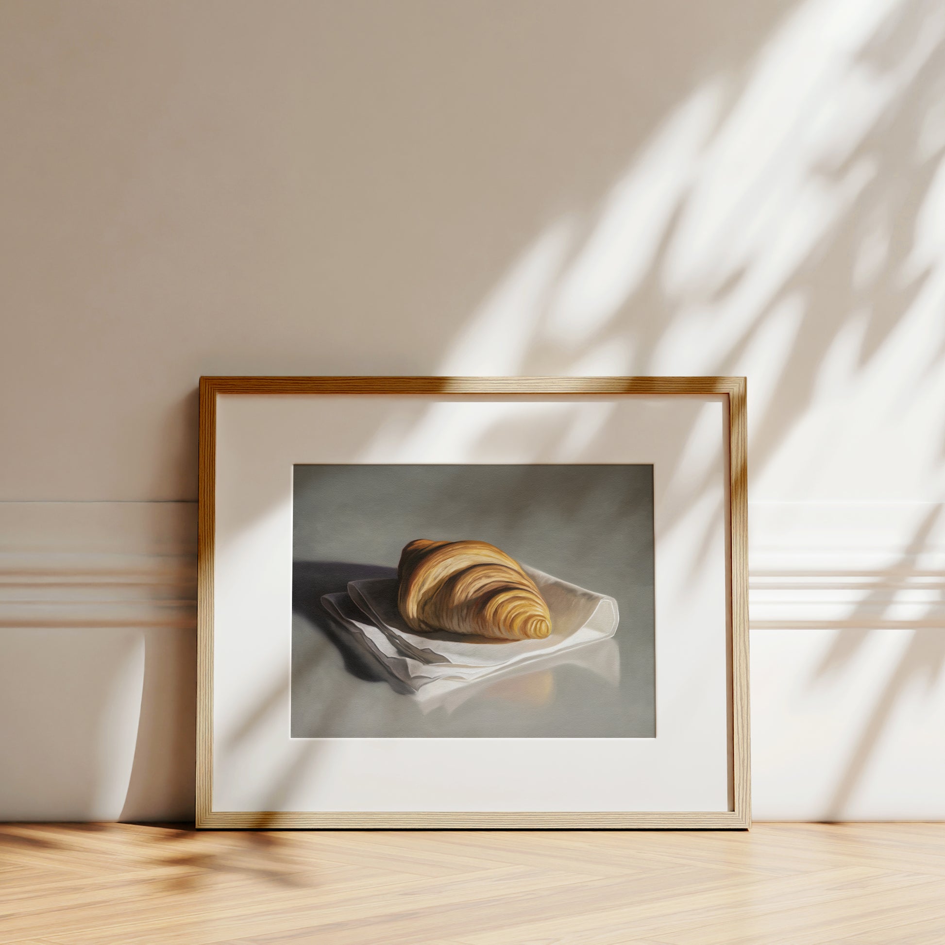 This artwork features a single freshly baked croissant resting on a napkin on a reflective surface.