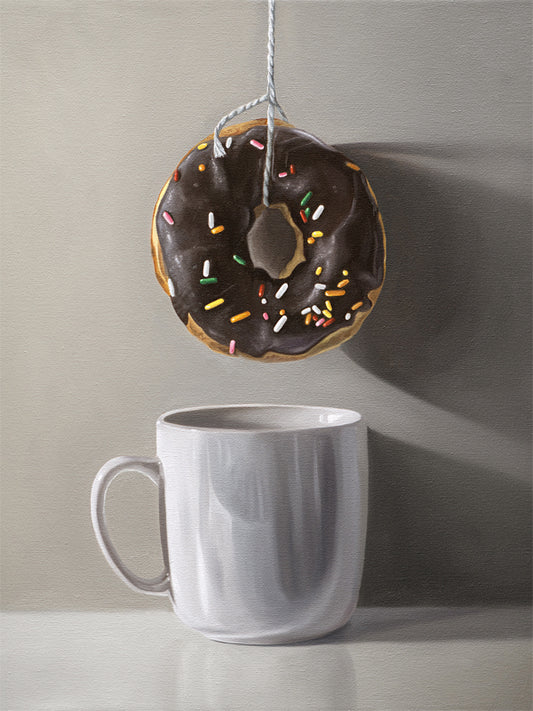 This artwork features a chocolate sprinkled doughnut suspended by a string over a white porcelain cup.