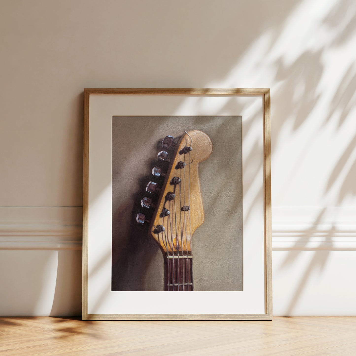 This artwork features an electric guitar head stock leaning on a warm grey surface with some nice dramatic lighting.