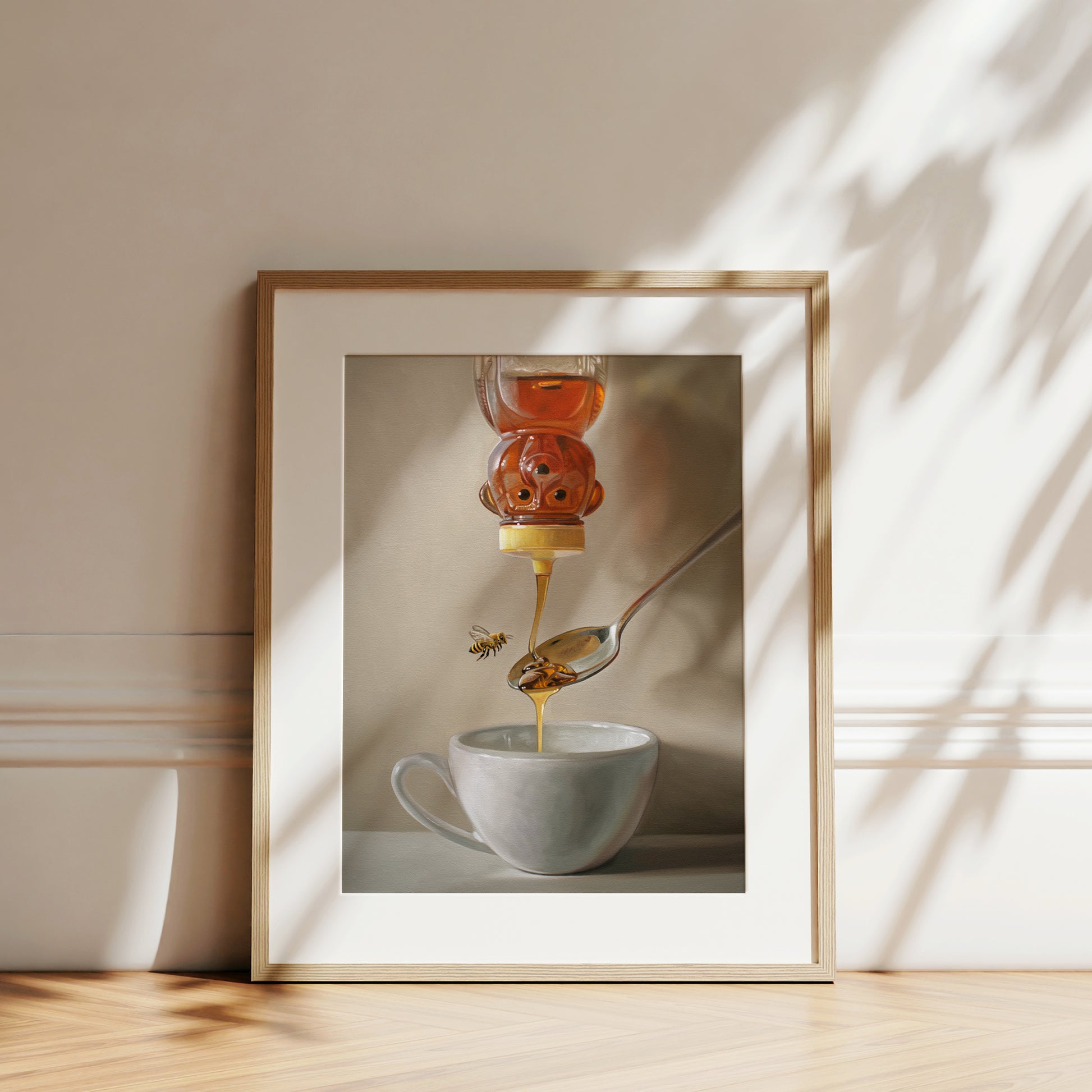 This artwork features a classic honey bear bottle turned upside down whilst golden honey spills into a spoon and cup of tea below.