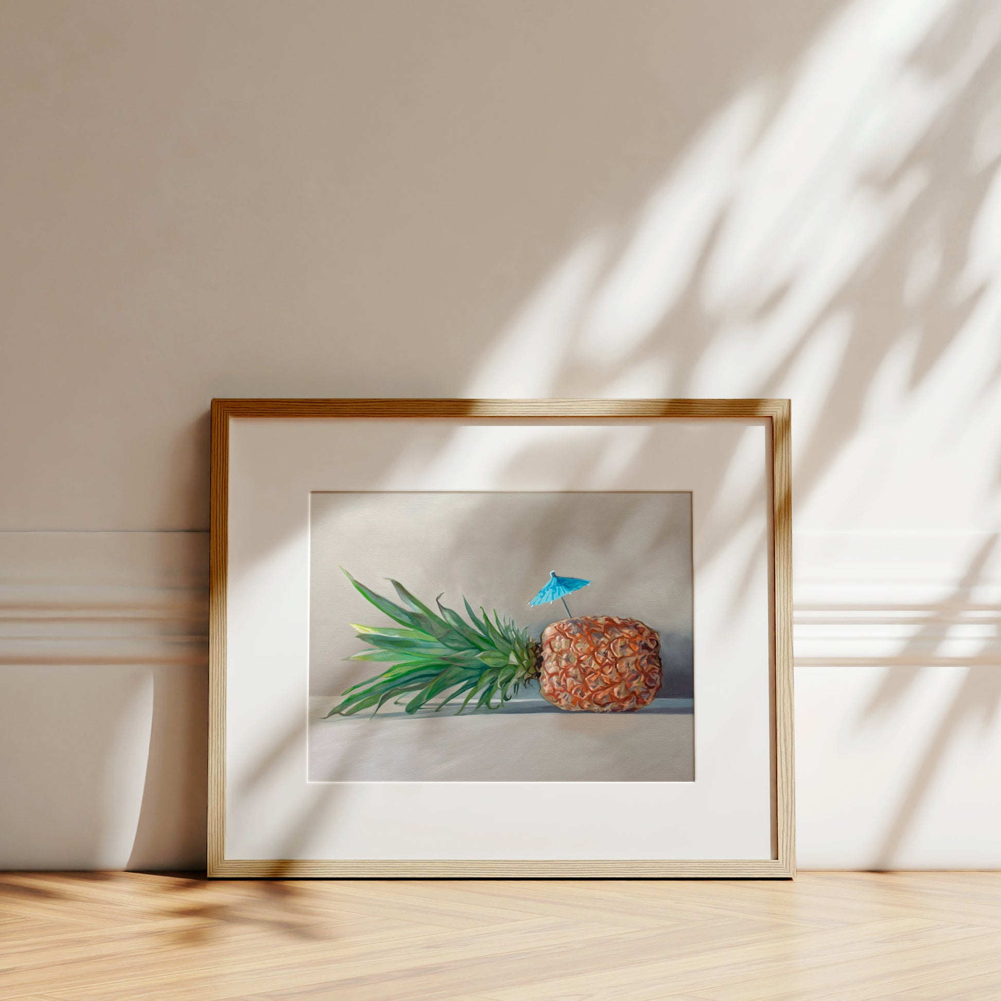 This artwork features a sideways resting pineapple with a blue tropical drink umbrella on top.