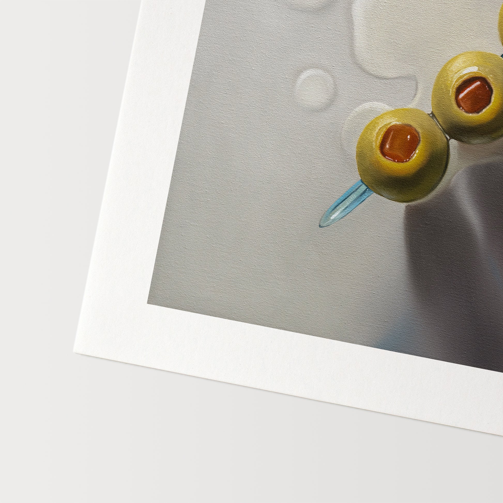This artwork features a trio of green olives on a blue cocktail sword with some nice dramatic lighting.