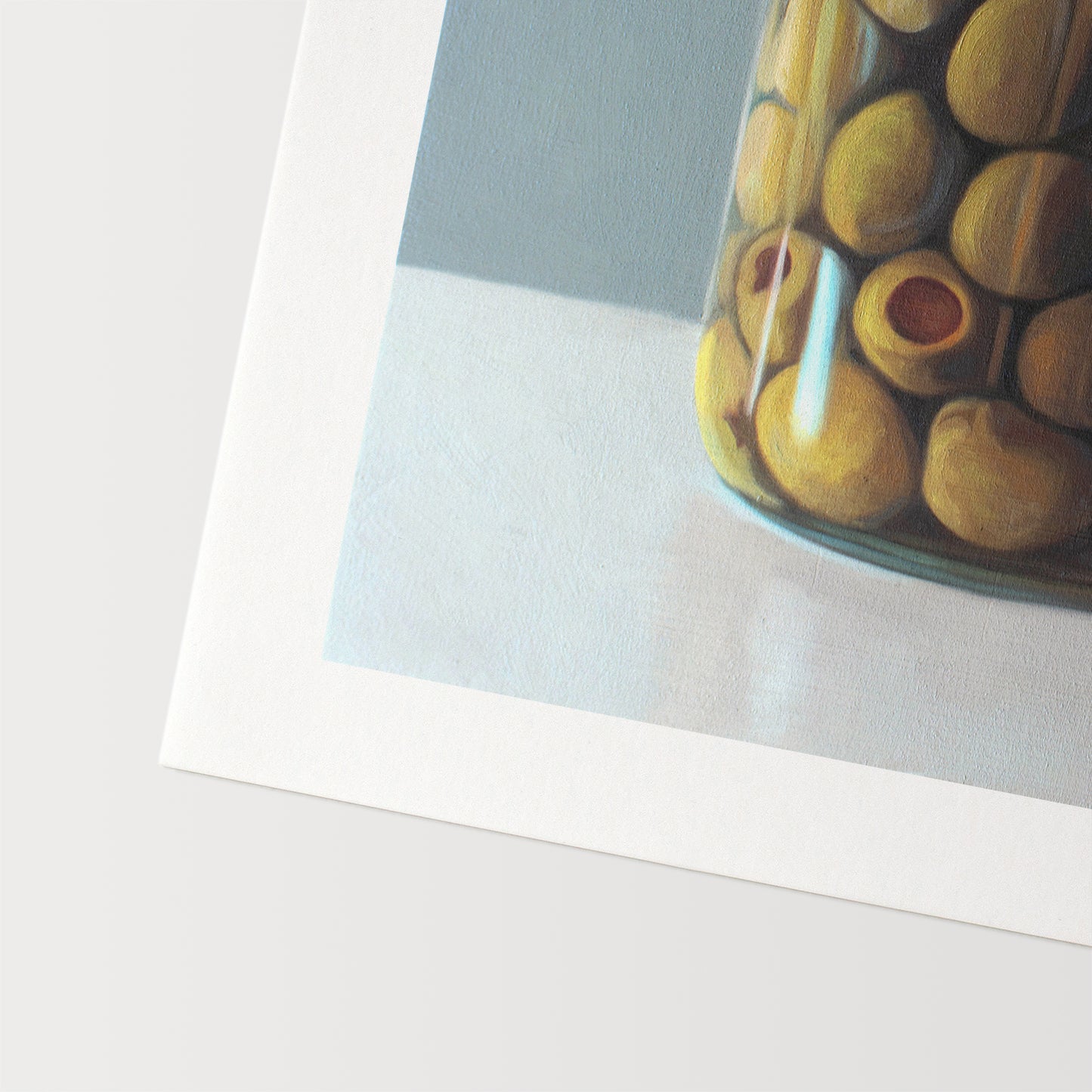 This artwork features a jar of green olives resting on a light, reflective surface with a muted blue/green background.