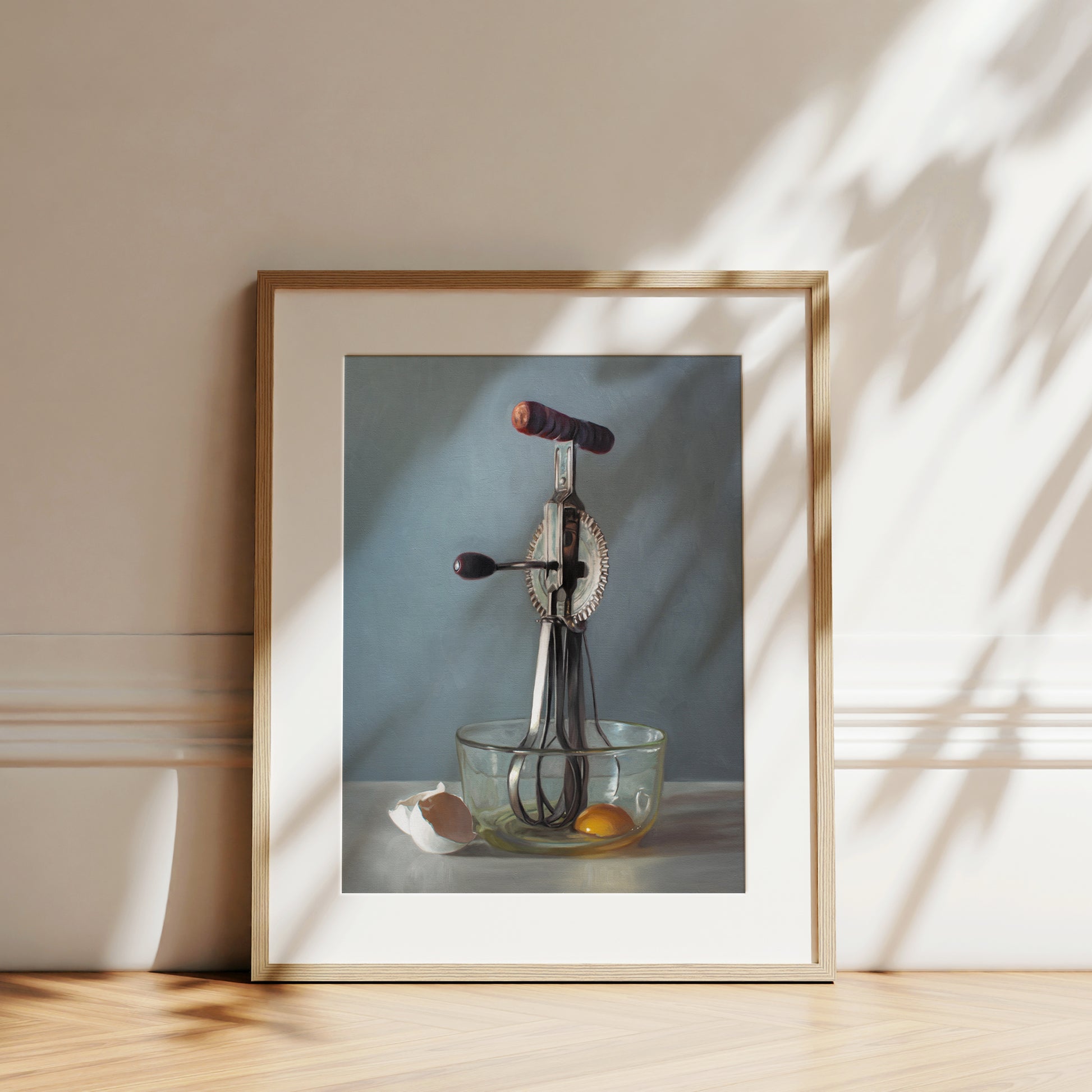 This artwork features an antique egg beater and a glass bowl containing an egg white the white shells juxtaposed on the left.