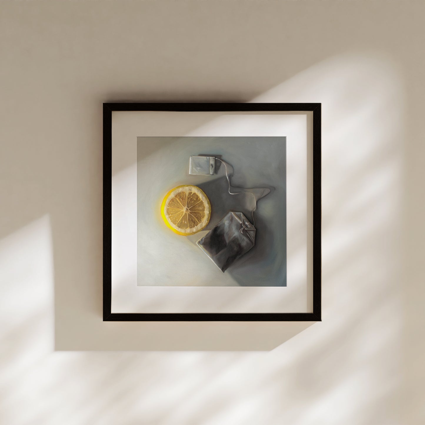 This artwork features a slice of lemon laying next to a tea bag on a light grey surface with dramatic lighting and cast shadows.