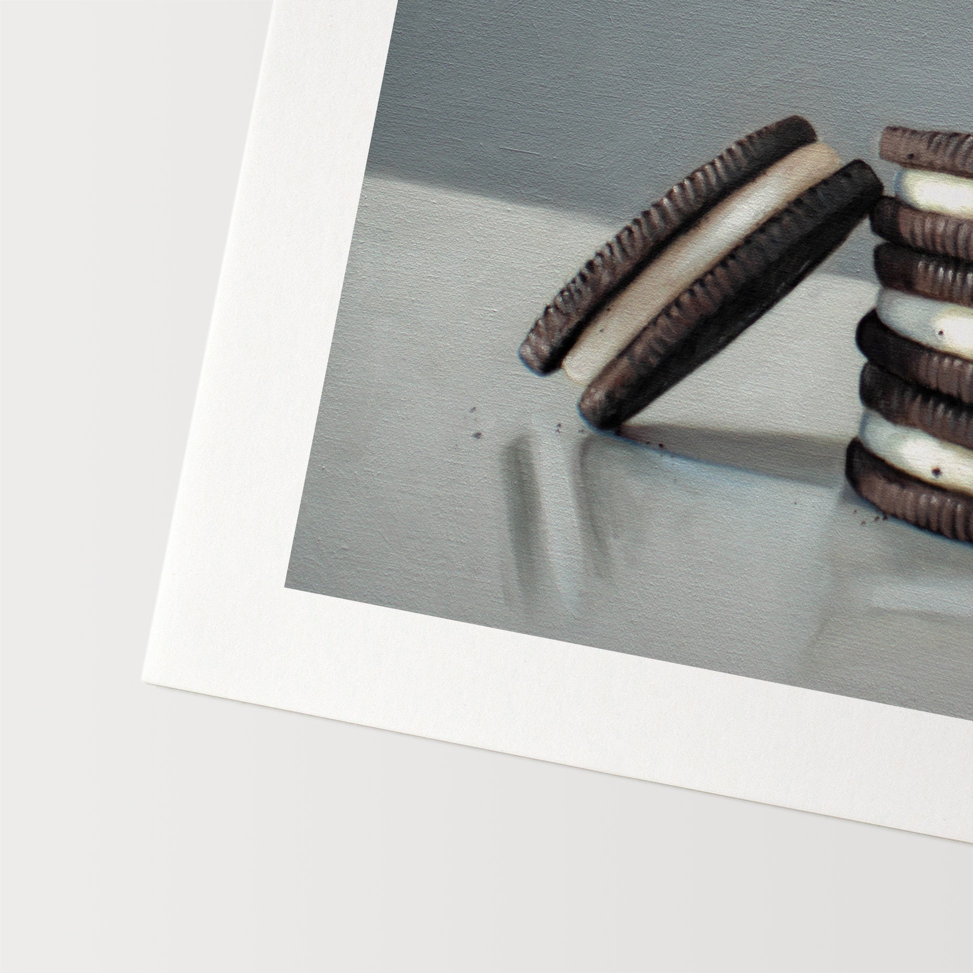 This artwork features a trio of Oreos on a light, reflective surface with dramatic lighting and cast shadows.