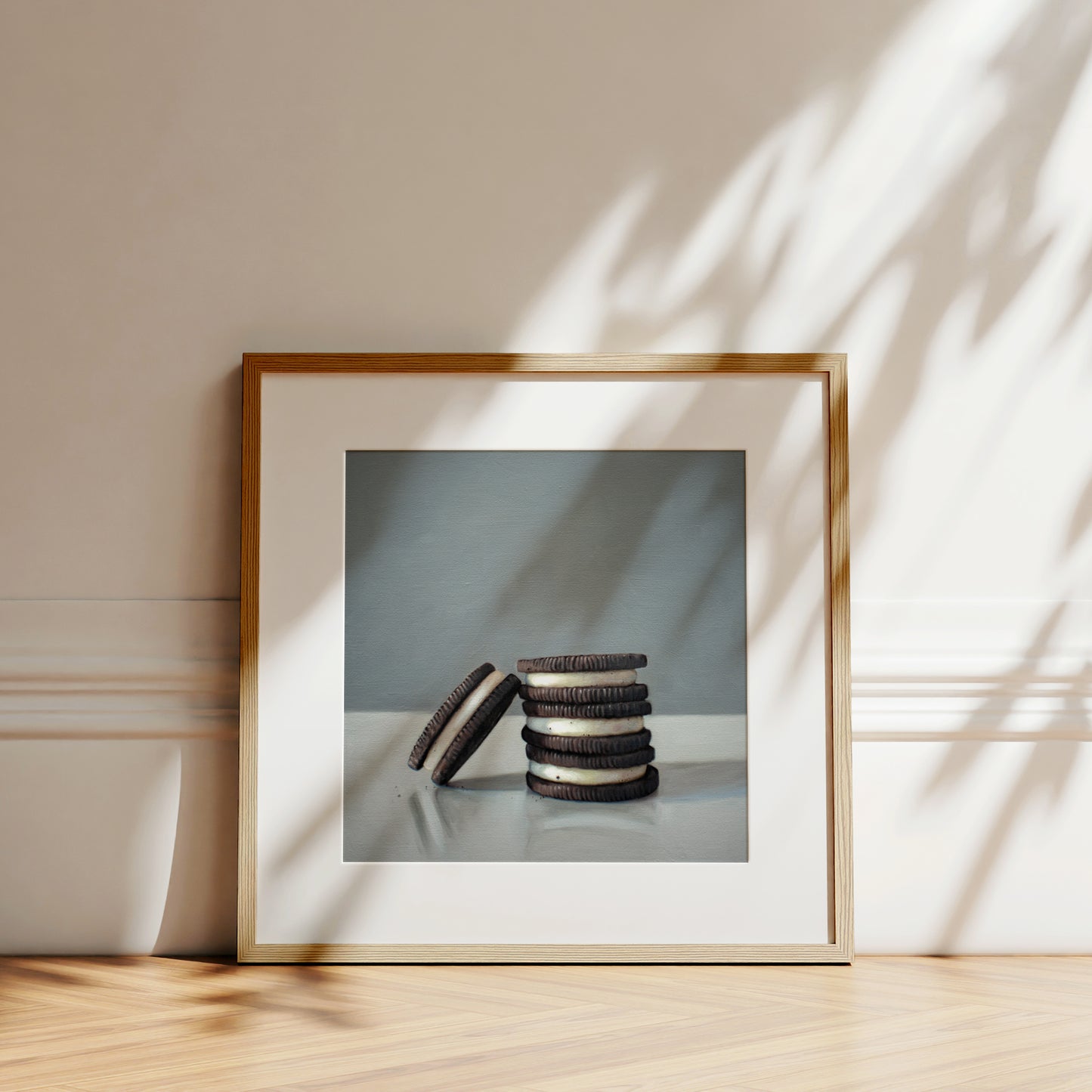 This artwork features a trio of Oreos on a light, reflective surface with dramatic lighting and cast shadows.