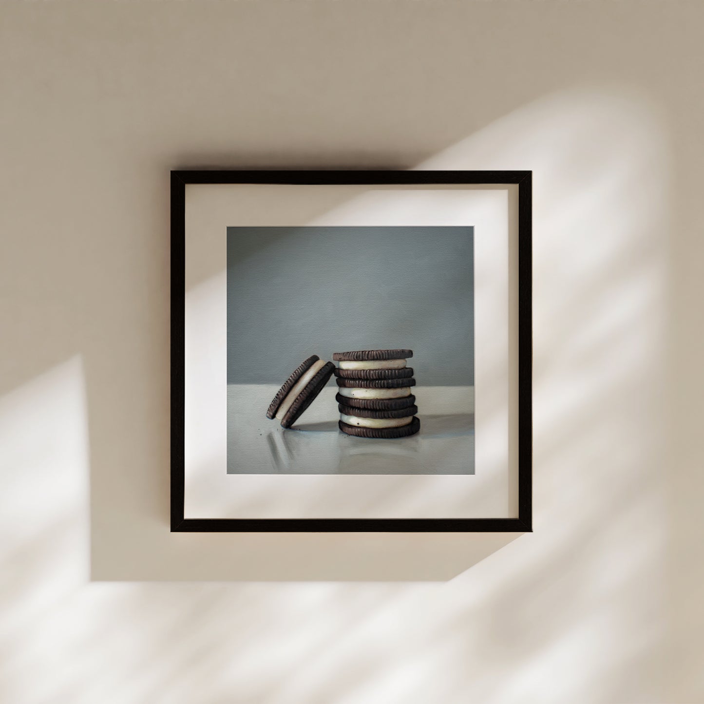 This artwork features a trio of Oreos on a light, reflective surface with dramatic lighting and cast shadows.