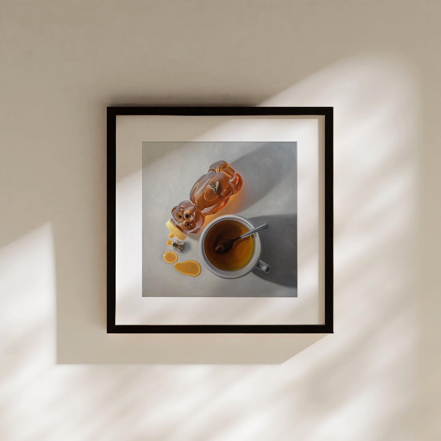 This artwork features a pair of honey bees inspecting a tipped honey bear bottle resting next to a cup of tea.
