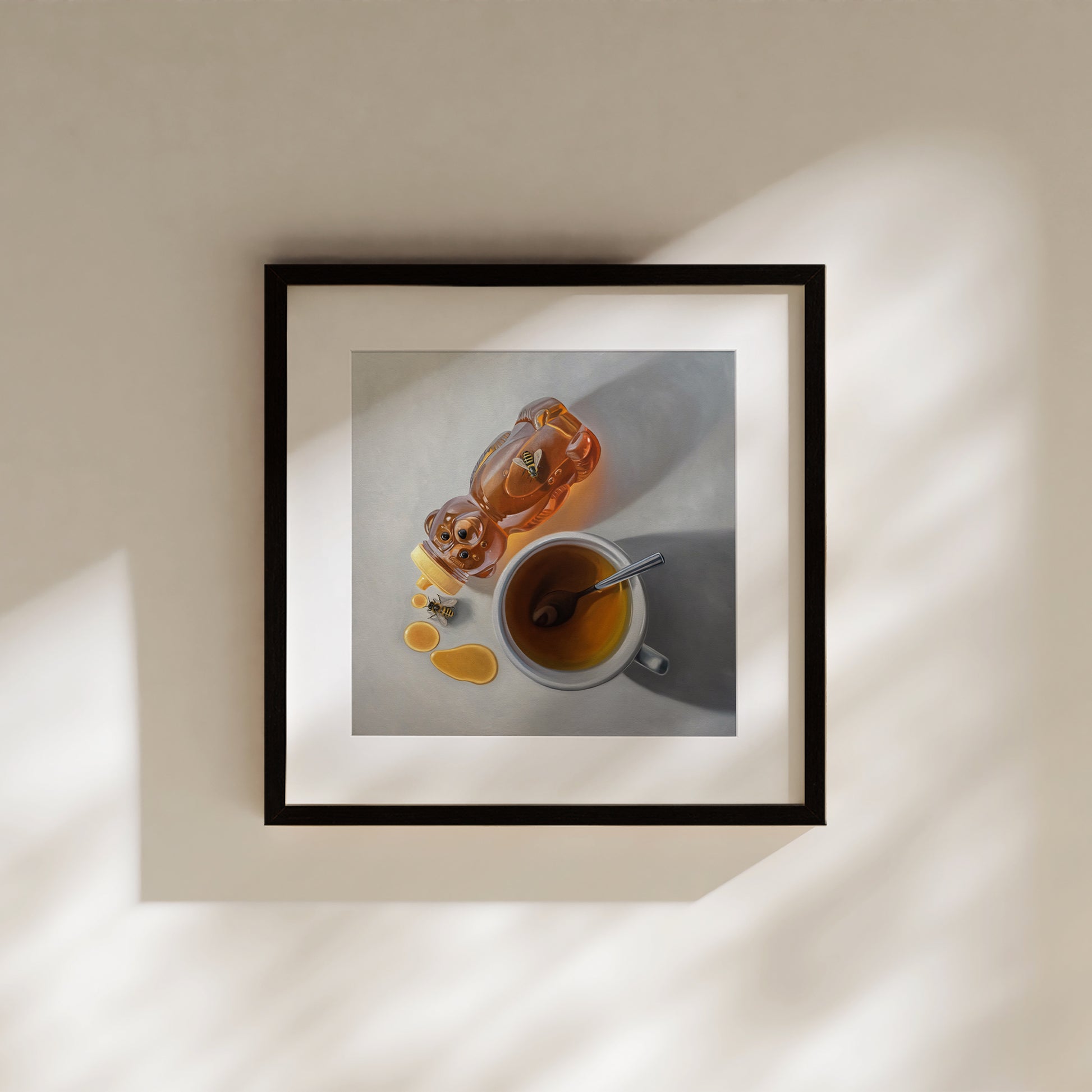 This artwork features a pair of honey bees inspecting a tipped honey bear bottle resting next to a cup of tea.