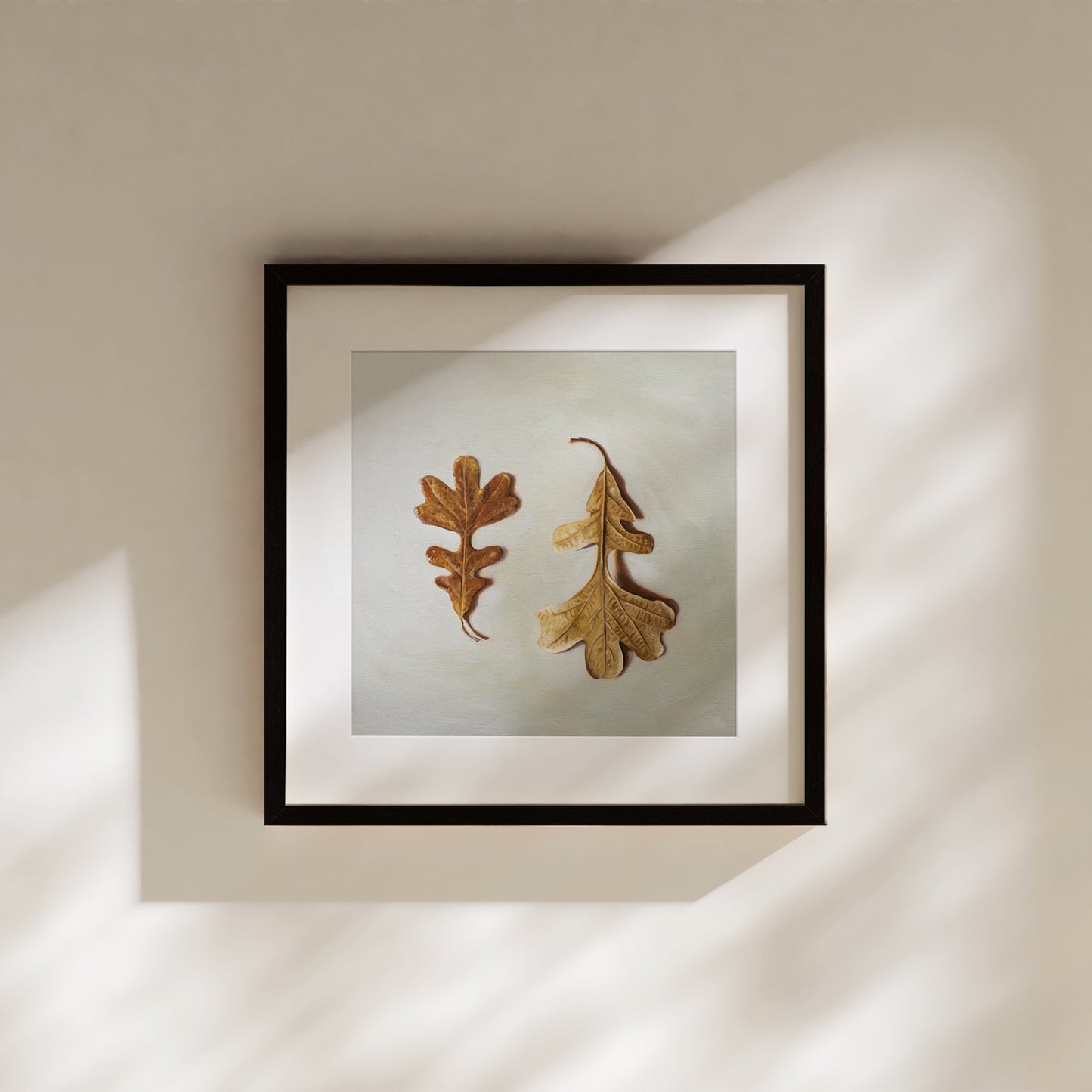 Autumn Oak Tree Leaves Fine Art Print by Lauren Pretorius: a duo of Oak Tree leaves laying on a light surface. One of the leaves faces upwards, while the other is flipped over and upside down.