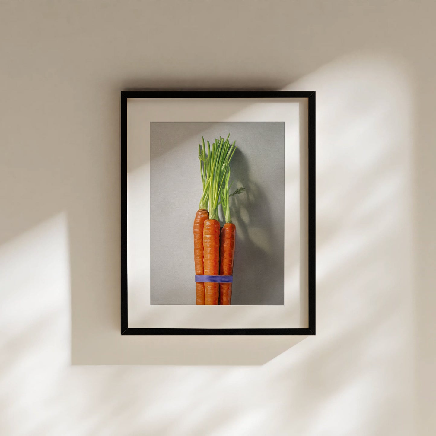Framed fine art print of a vibrant orange carrot bunch with green tops, tied with a blue band.
