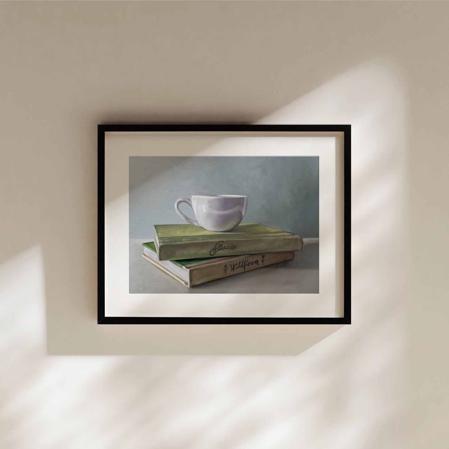 Framed fine art print of a white coffee cup on two vintage green books, with soft shadows.