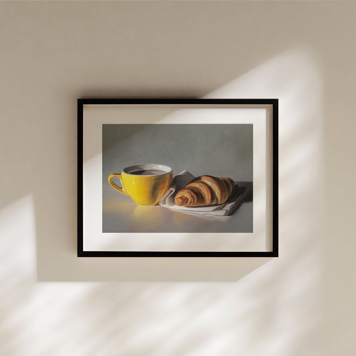 Framed fine art print of a yellow coffee cup and a golden croissant on a white napkin.