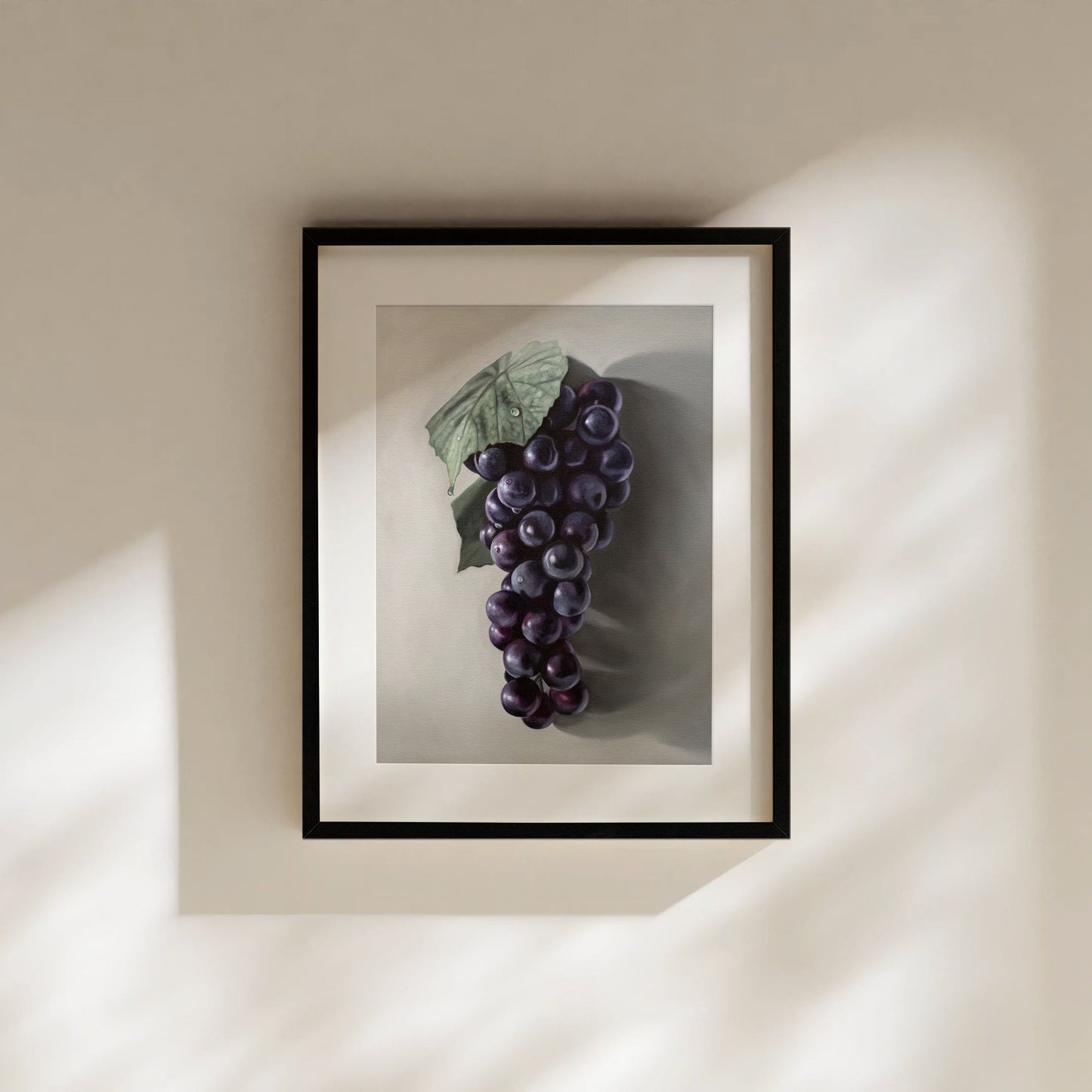Framed fine art print of a vibrant purple Concord grape cluster with a green leaf, on a light background.