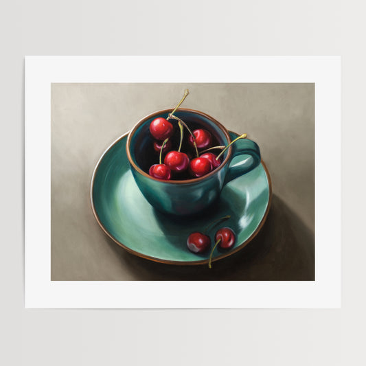 Cup of Cherries Fine Art Print by Lauren Pretorius: red cherries inside a blue green ceramic cup with a matching saucer, with a few cherries scattered outside the cup on a grey surface.