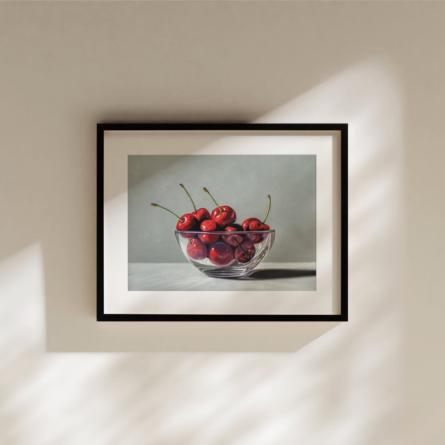 Fine art print of a glass bowl overflowing with vibrant red cherries, framed in black.