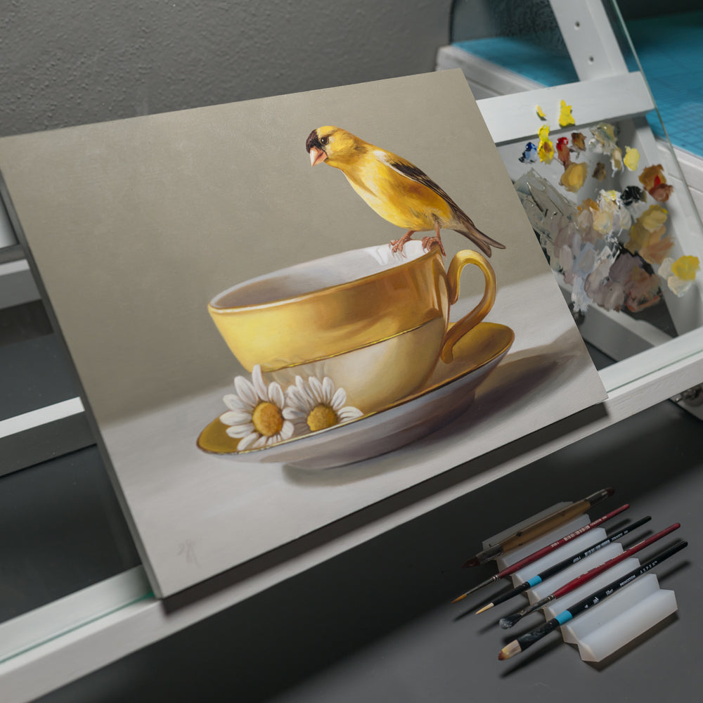 Goldfinch & Yellow Cup 14" x 11" Original Oil Painting by Lauren Pretorius: a goldfinch perched on a gold teacup with white flowers on a gray background