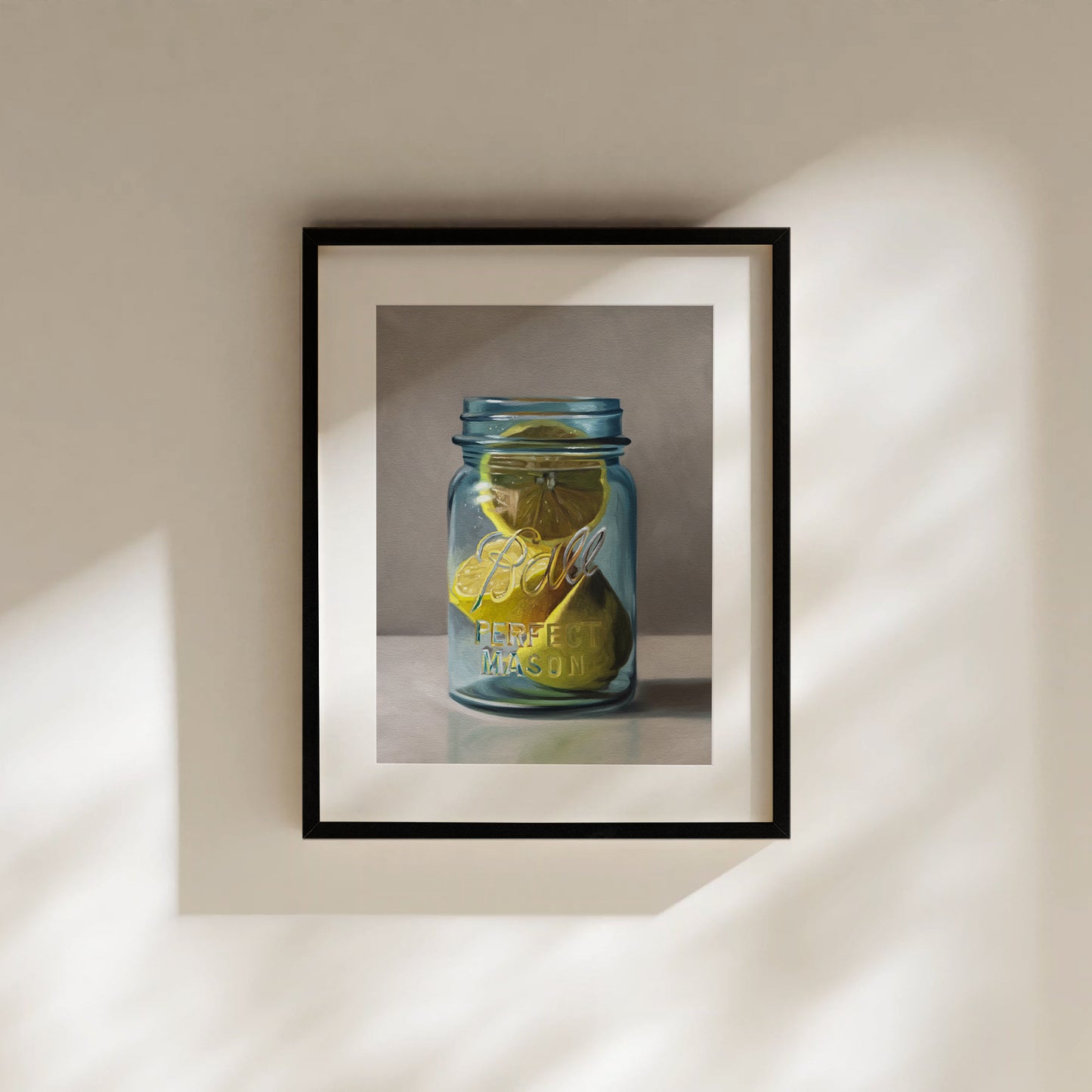 Framed fine art print of yellow lemons in a blue Ball Perfect Mason jar, hanging on a light wall.