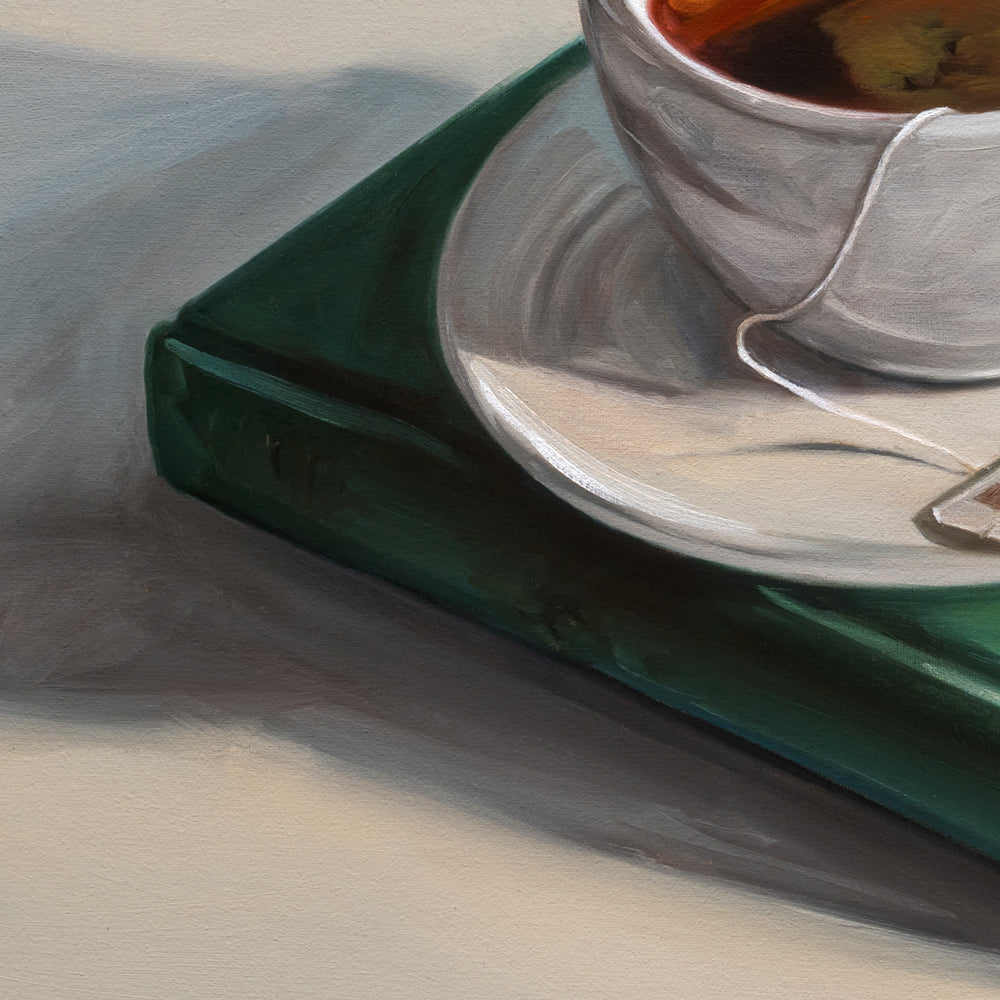 Original 12x12 oil painting of a white porcelain teacup resting on a vintage turquoise book with soft, warm lighting.