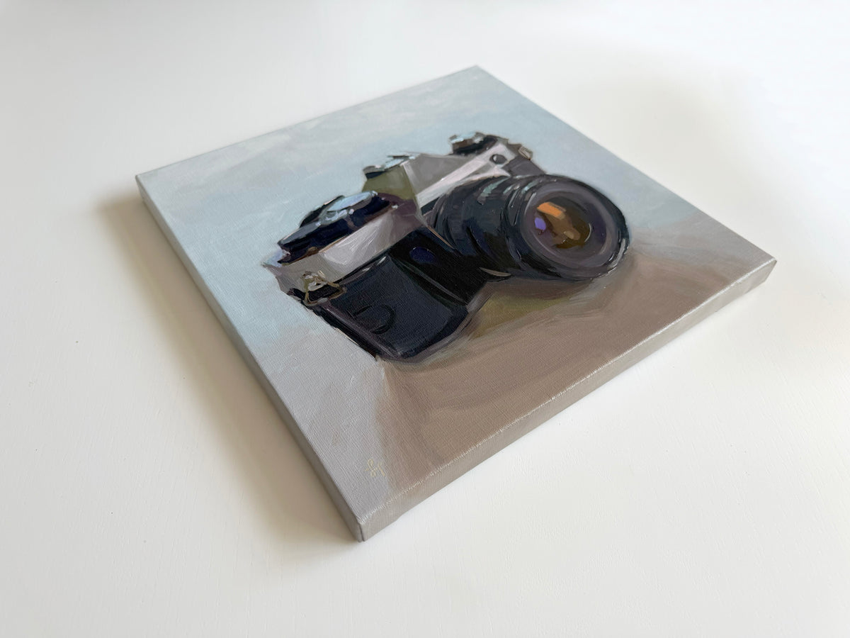 Original 12x12 inch oil painting on linen featuring a vintage film camera in soft blue and neutral tones.
