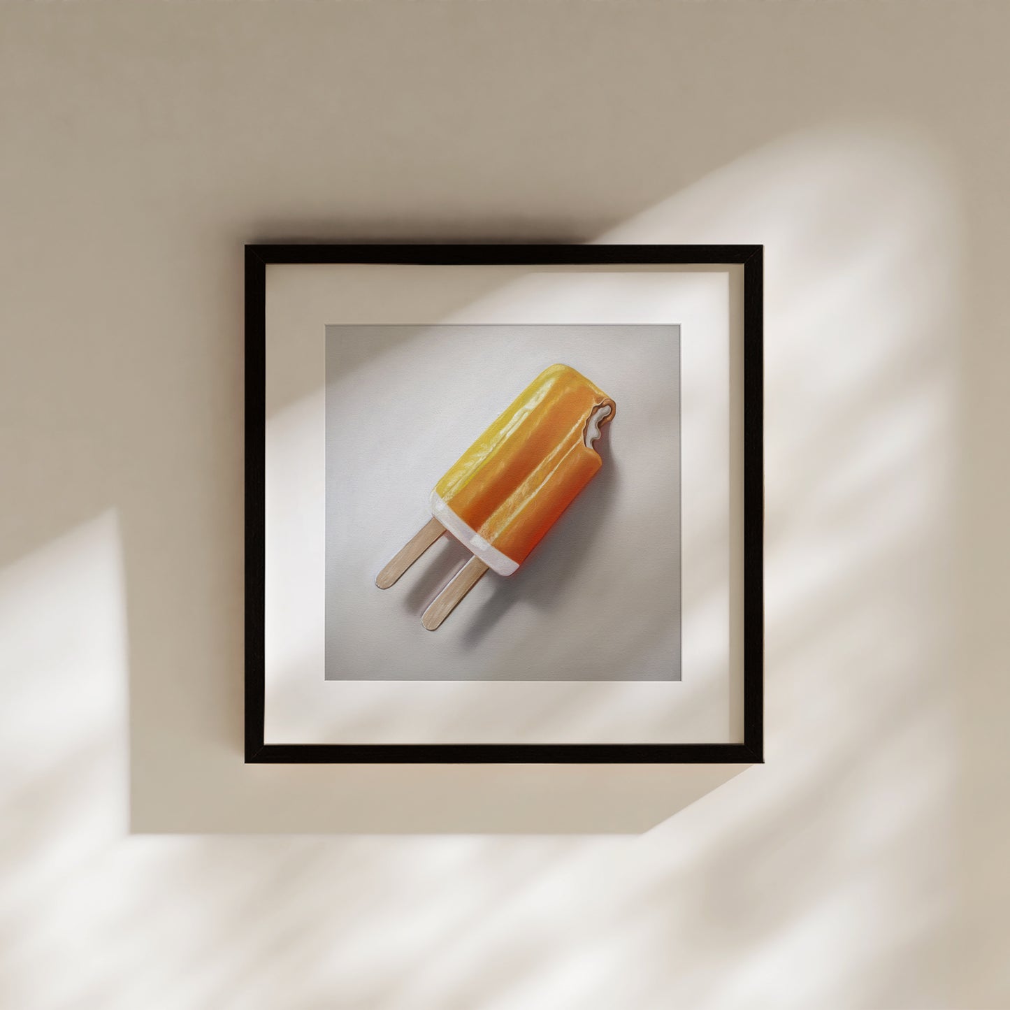 Framed fine art print of an orange dreamsicle popsicle with a bite taken out, on a light background.