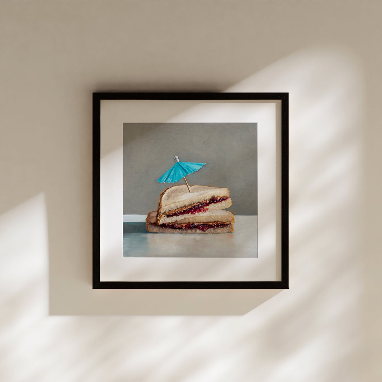 Framed art print of a realistic peanut butter and jelly sandwich with a blue cocktail umbrella.