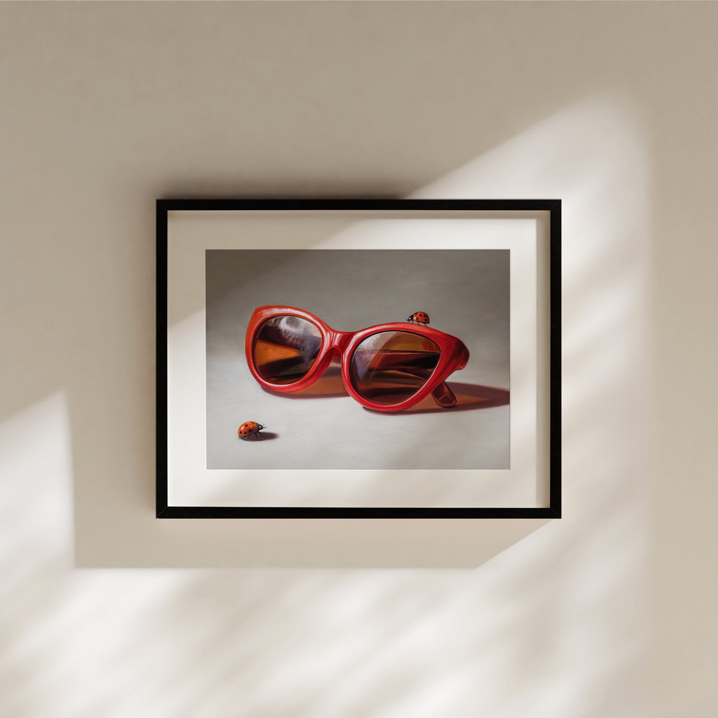 Red Ladies Trio Fine Art Print by Lauren Pretorius: red sunglasses with a reflective surface, two ladybugs on and around them against a neutral background.