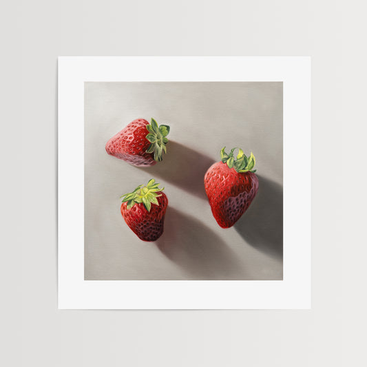 Strawberry Trio Fine Art Print by Lauren Pretorius: a trio of bright red strawberries resting on a neutral grey surface with dramatic light and shadows.