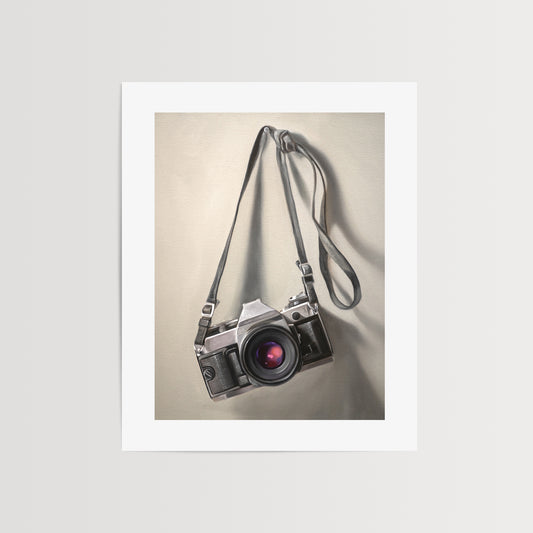 Vintage Film Camera Fine Art Print by Lauren Pretorius: a vintage 35mm camera hanging from its strap with some nice dramatic lighting.