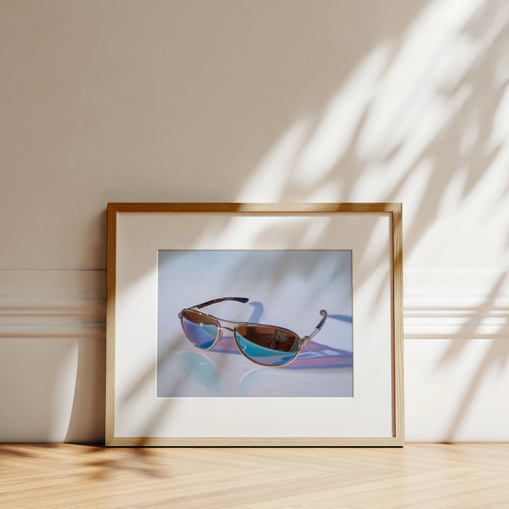 This artwork features a pair of reflective aviator sunglasses resting on a light, reflective surface.