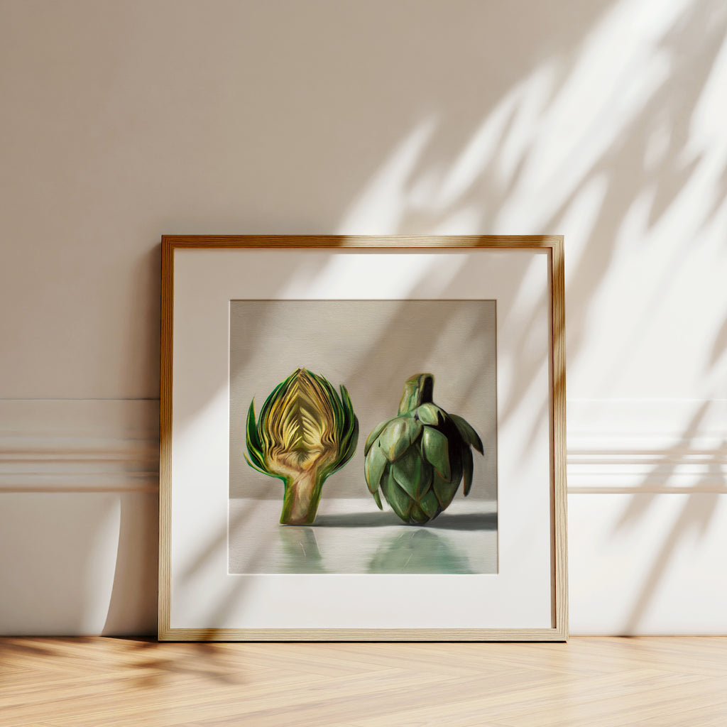 This artwork features an artichoke sliced in half an strategically placed on a light reflective surface.