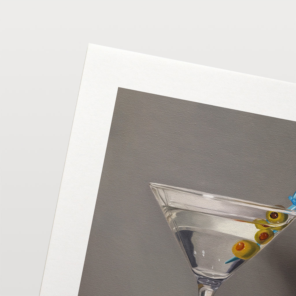 This artwork features a martini with a bumble bee perched on a blue plastic cocktail sword with a trio of green olives and a neutral, minimalistic backdrop.