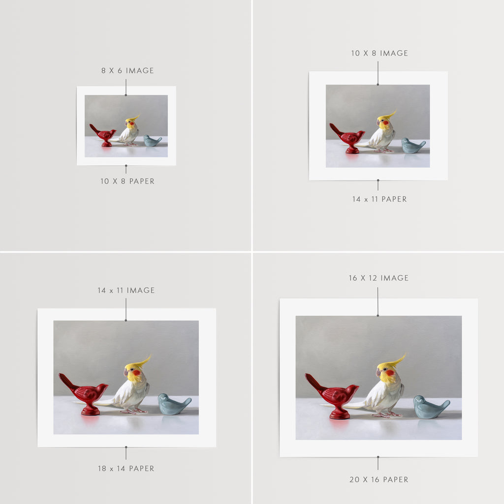 This artwork features a white cockatiel standing in between a red and blue bird figurine on a light, reflective surface with dramatic lighting.