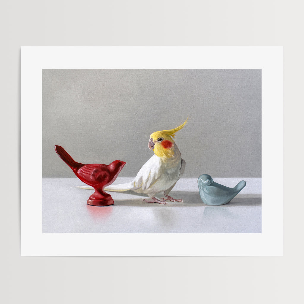 This artwork features a white cockatiel standing in between a red and blue bird figurine on a light, reflective surface with dramatic lighting.