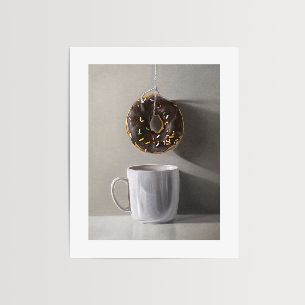 This artwork features a chocolate sprinkled doughnut suspended by a string over a white porcelain cup.