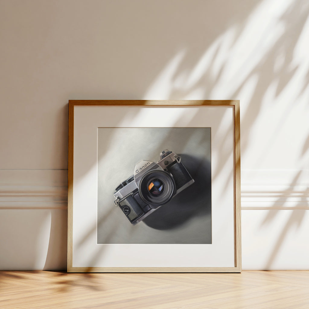 This oil painting features a vintage Canon AE-1 camera resting on a neutral surface with dramatic side lighting.