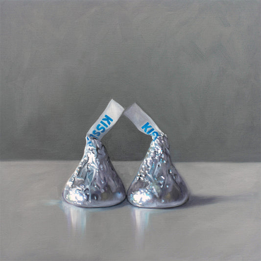 This artwork features a pair of classic milk chocolate drops on a reflective surface with a dark grey background.