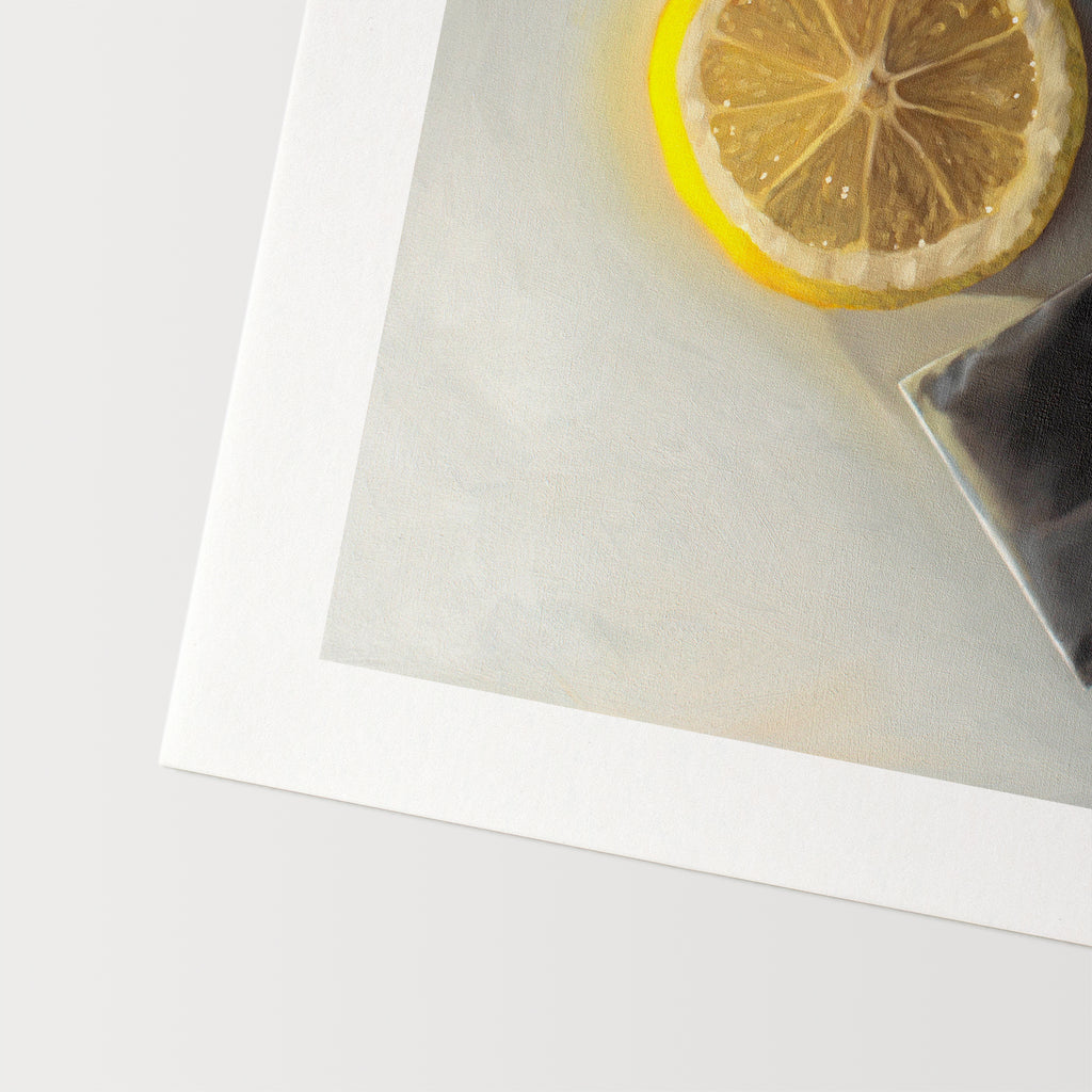 This artwork features a slice of lemon laying next to a tea bag on a light grey surface with dramatic lighting and cast shadows.