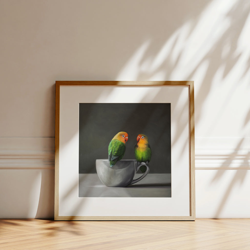 This artwork features a pair of Fischer’s Lovebirds perched on a white porcelain cup.