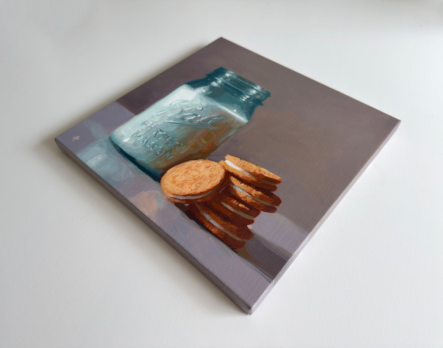 A square canvas painting depicting a blue glass mason jar and a stack of golden-brown cookies, shown at an angle on a light gray background.