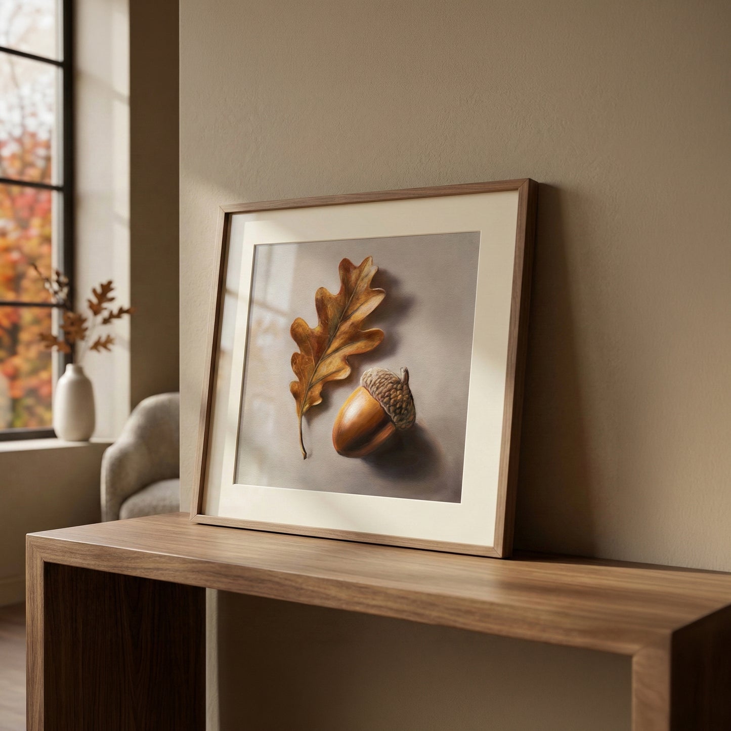 Framed fine art print of a detailed brown oak leaf and acorn on a light background, displayed on a wooden table.