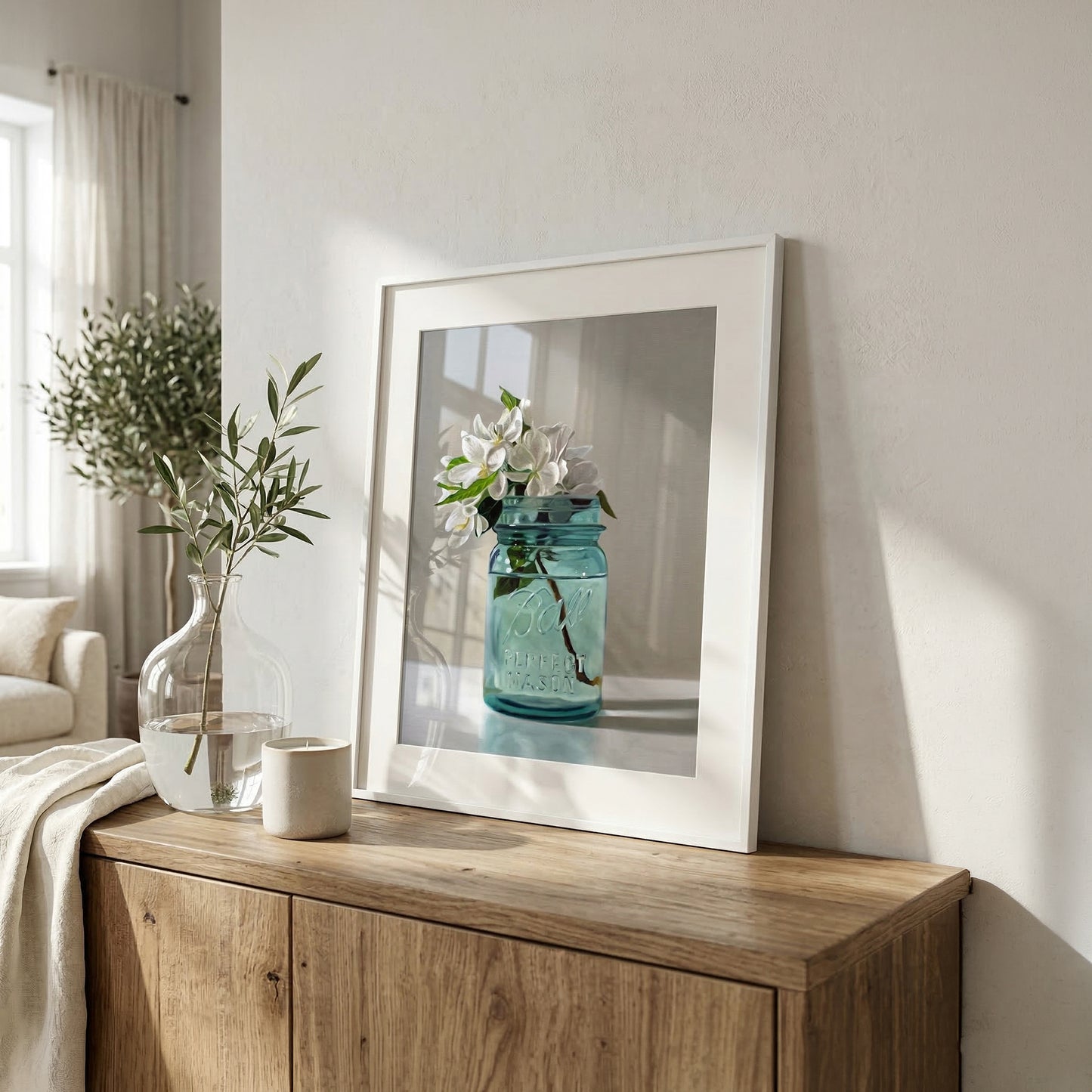 Framed fine art print of white apple blossoms in a vintage blue mason jar on a wooden cabinet.